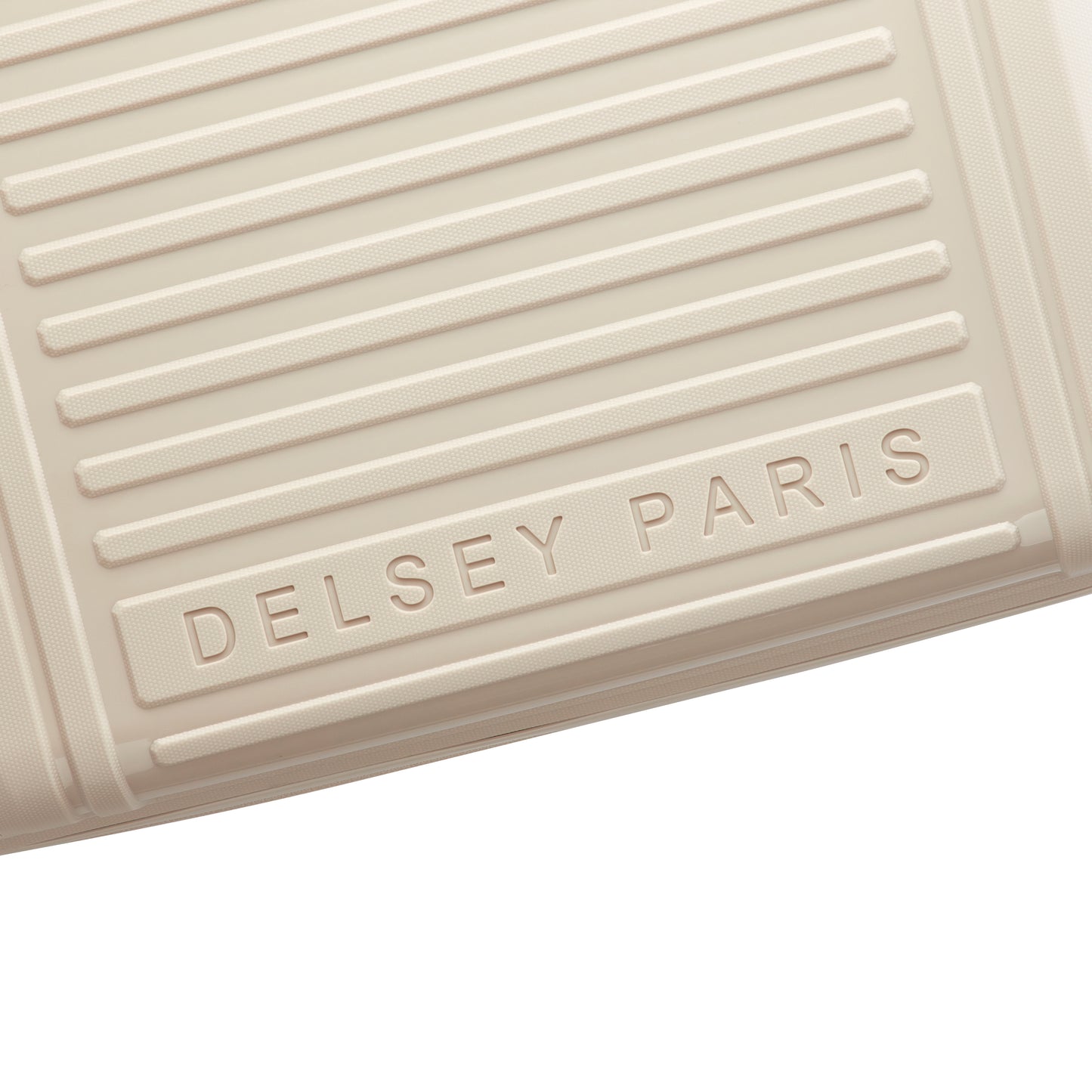 Detalhe em close da superfície texturizada em bege claro de mala de bordo expandível da DELSEY, destacando o nome gravado da marca francesa de malas de viagem.