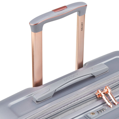 Detalhe da alça retrátil em alumínio com acabamento em tom cobre e pega superior ergonômica de mala média expansível cinza da DELSEY, destacando zíper antifurto e design moderno.