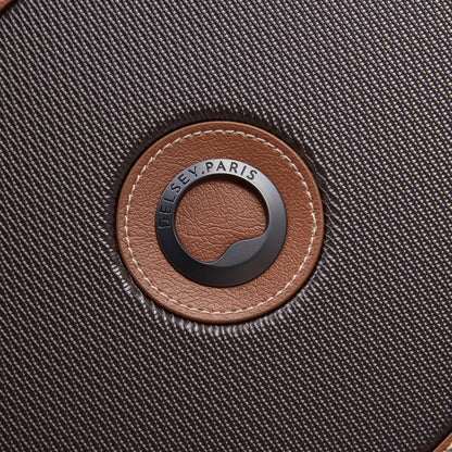 Close-up do logo da marca DELSEY Paris em mala de viagem média na cor chocolate com textura fina e detalhes em couro marrom.