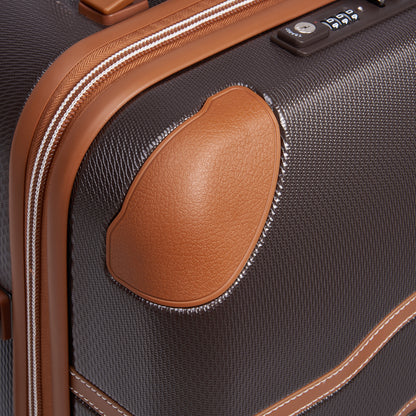 Detalhe da mala média DELSEY em tom chocolate, com acabamento em couro sintético marrom, zíper antifurto e design rígido, ideal para viagem segura e durável.