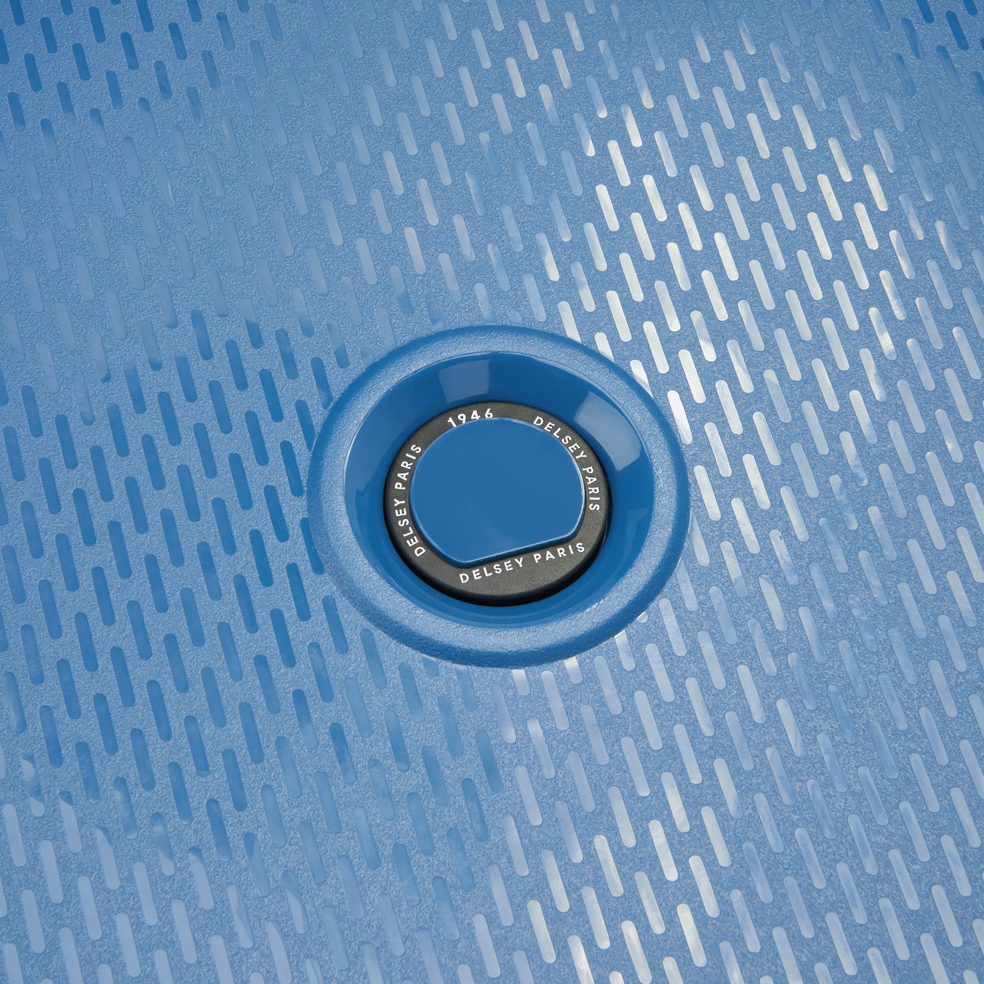 Detalhe do logo DELSEY Paris em mala azul intenso de polipropileno rígido com textura moderna, demonstrando design premium e durabilidade.