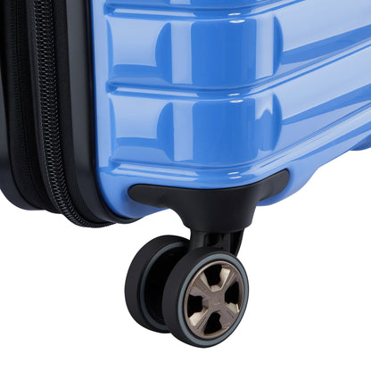 Roda dupla preta com acabamento metálico em mala de bordo azul claro expansível da DELSEY, destacando durabilidade e design moderno em material rígido.