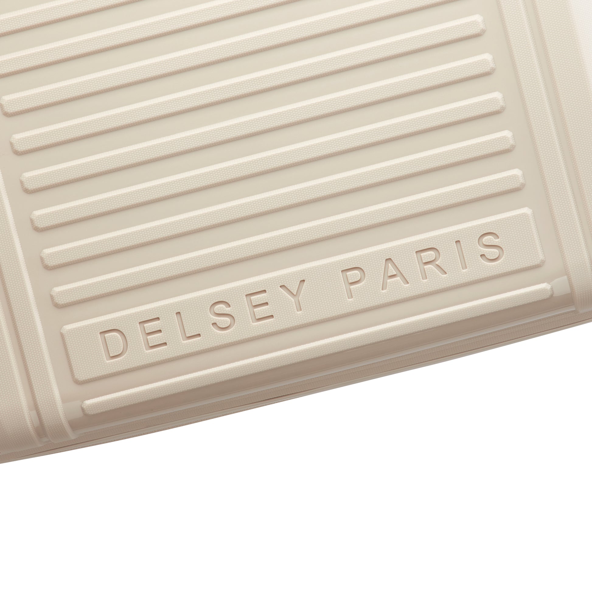 Detalhe em close da superfície texturizada em bege claro de mala de bordo expandível da DELSEY, destacando o nome gravado da marca francesa de malas de viagem.