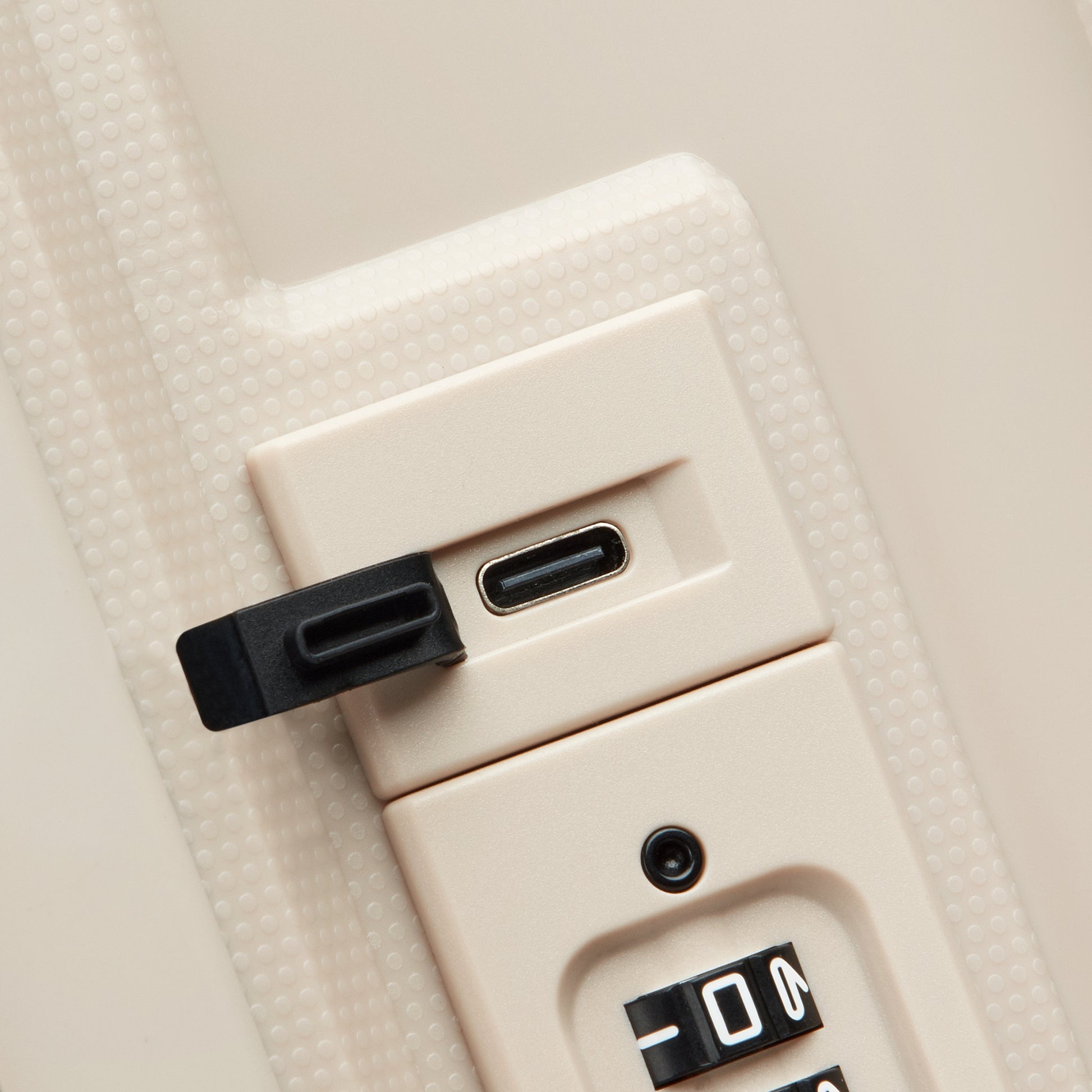 Fechadura com combinação segura e entrada USB protegida por tampa, em acabamento bege, parte da mala de bordo expansível da DELSEY, garantindo proteção e funcionalidade.