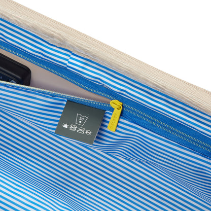 Interior da mala de bordo bege com forro listrado azul e branco, detalhe do zíper amarelo com a marca DELSEY, evidenciando qualidade e acabamento premium.