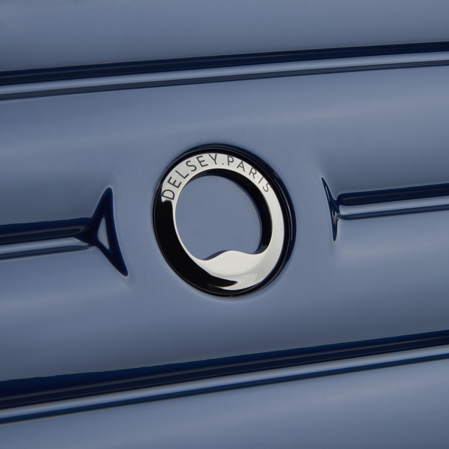 Detalhe do logo DELSEY Paris em mala de bordo rígida azul escuro, evidenciando acabamento premium e design elegante da marca francesa reconhecida mundialmente.