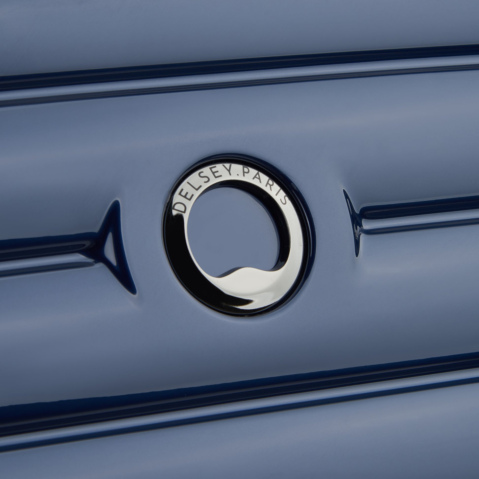 Detalhe do logo DELSEY Paris em mala de bordo rígida azul escuro, evidenciando acabamento premium e design elegante da marca francesa reconhecida mundialmente.