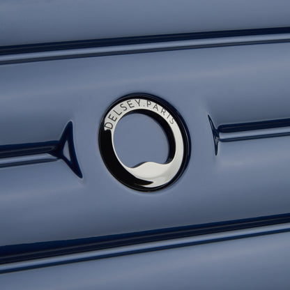 Detalhe do logo DELSEY Paris em mala de bordo rígida azul escuro, evidenciando acabamento premium e design elegante da marca francesa reconhecida mundialmente.