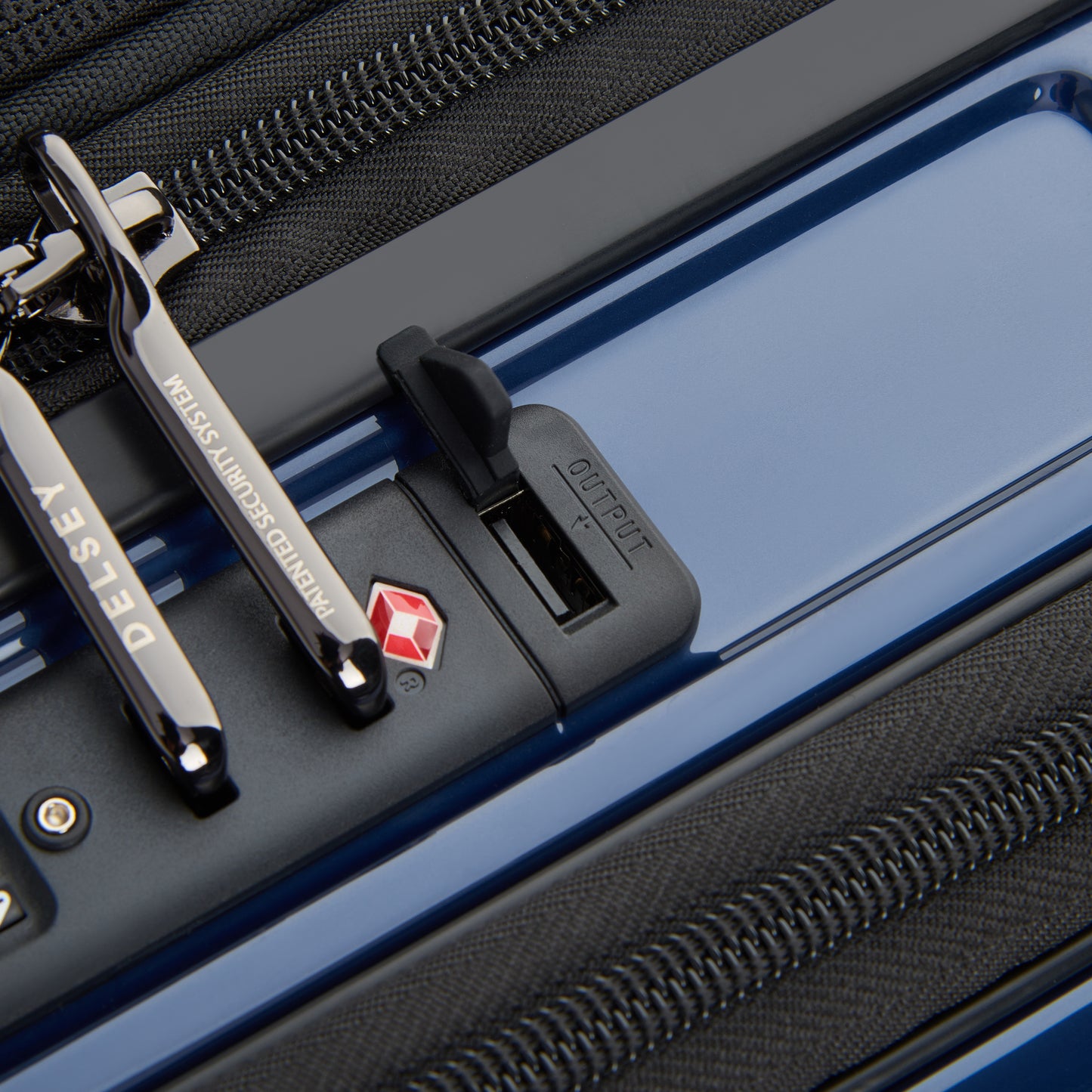 Fechadura TSA integrada com sistema antifurto em mala rígida azul escuro da DELSEY, com zíperes reforçados e design moderno para maior segurança em viagens.