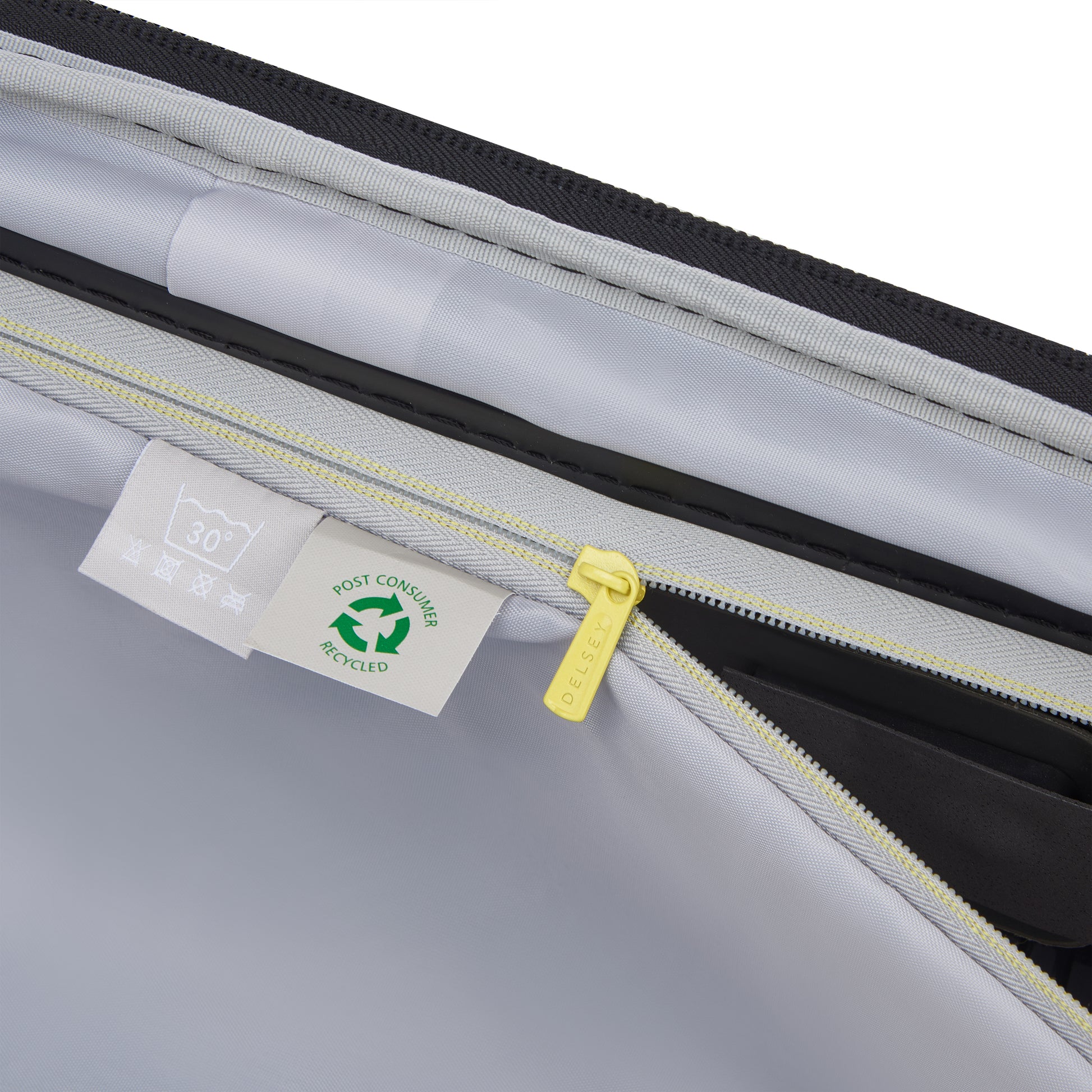 Detalhe interno da mala de bordo DELSEY com zíper amarelo, bolso organizado e etiqueta indicando material reciclado, destacando durabilidade e design premium.