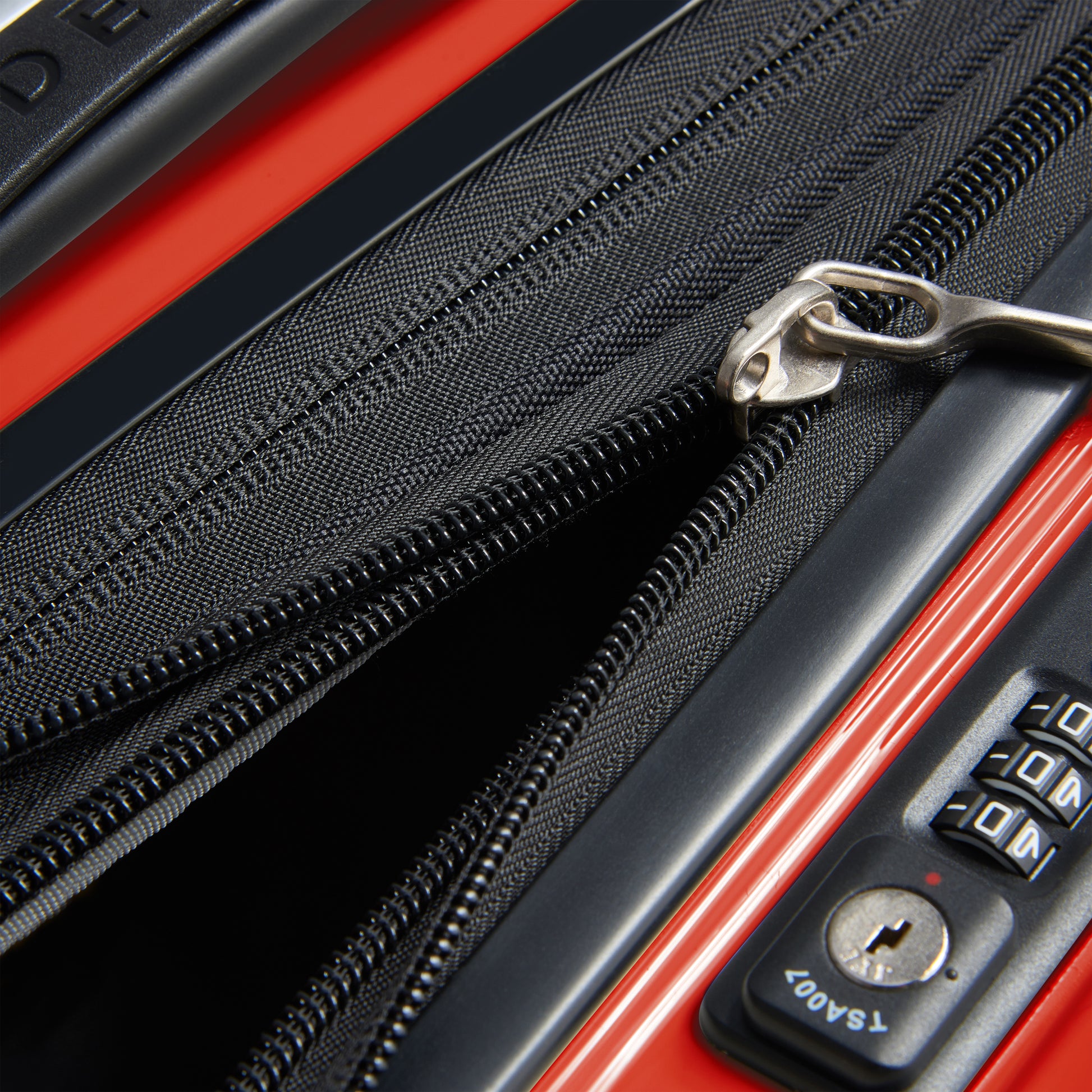 Detalhe do zíper antifurto em mala rígida laranja da DELSEY, coleção Shadow 5.0, destacando expansão e segurança para malas de bordo com porta notebook.