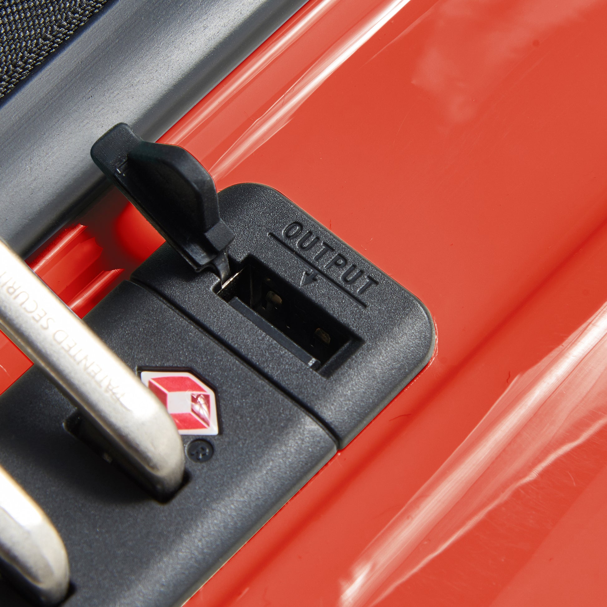 Detalhe do zíper antifurto com conexão USB embutida em mala rígida de bordo expansível laranja da DELSEY, ideal para viagens seguras e organizadas.