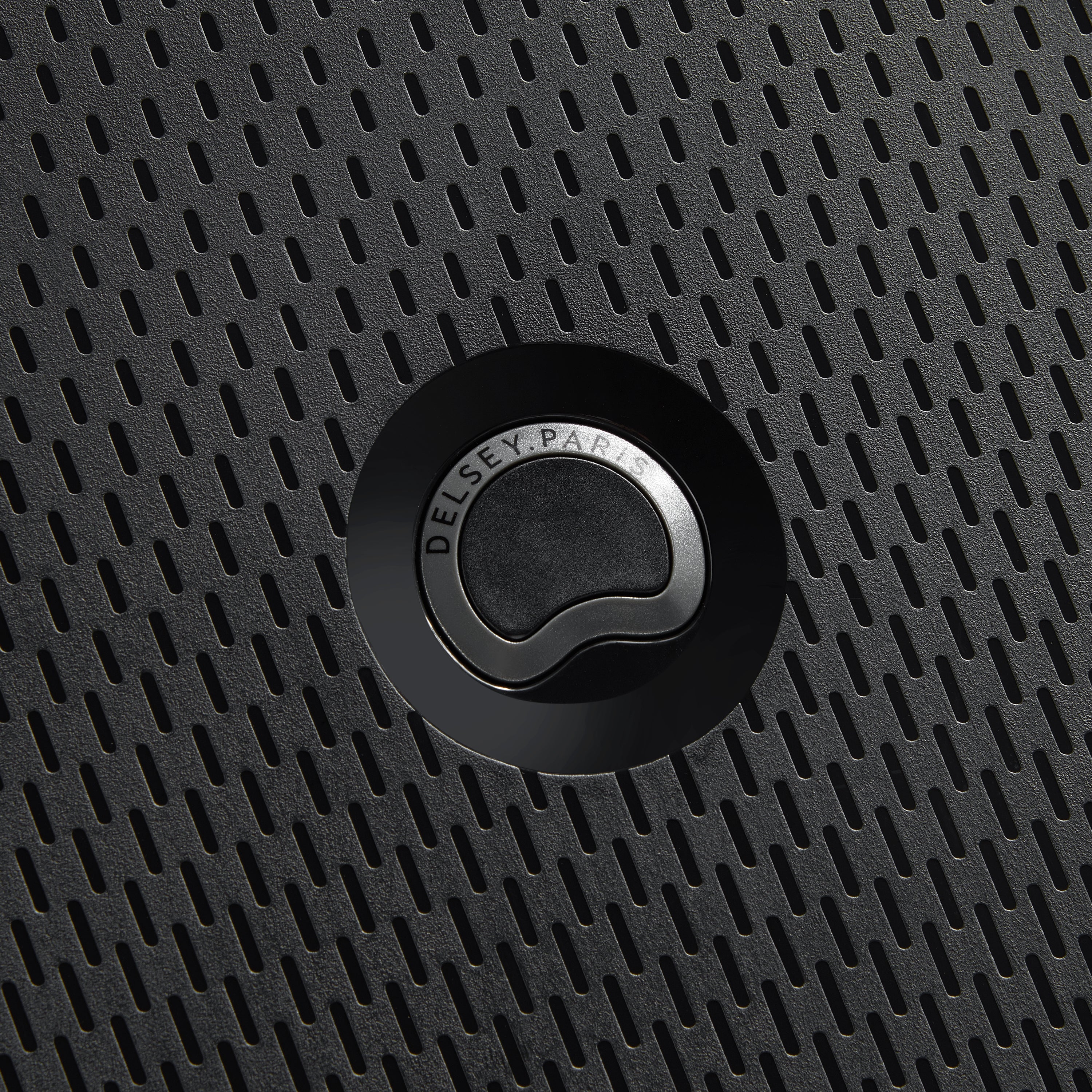 Detalhe do fecho preto com textura perfurada na superfície da mala de bordo expansível preta da DELSEY, evidenciando design moderno e durabilidade.