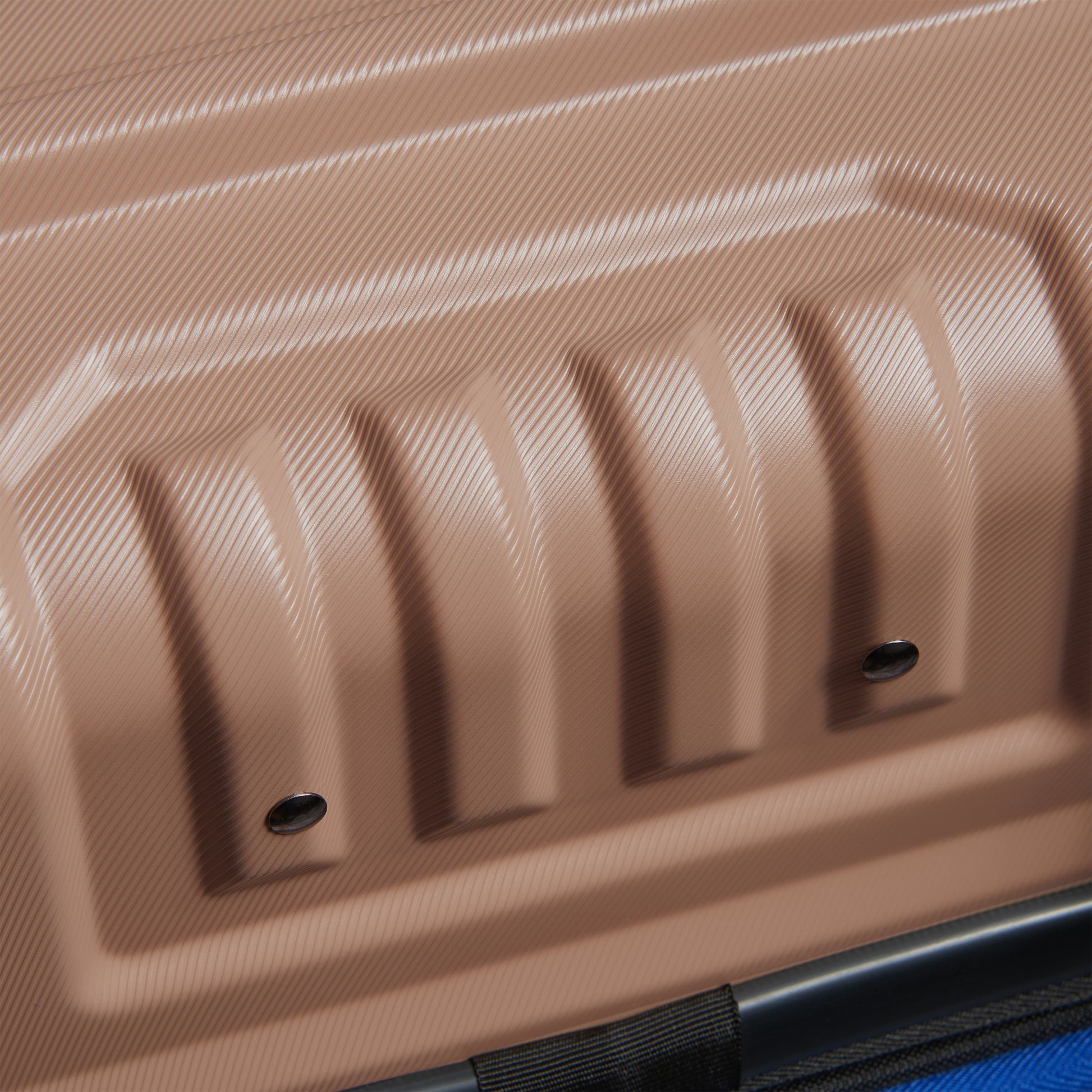 Detalhe da superfície rígida em policarbonato bege com textura fina e design robusto de mala de bordo expansível da DELSEY, destacando durabilidade e modernidade.