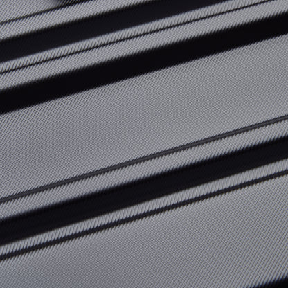 Detalhe texturizado da superfície cinza escuro da mala rígida DELSEY, destacando design resistente e acabamento refinado em material robusto e durável.